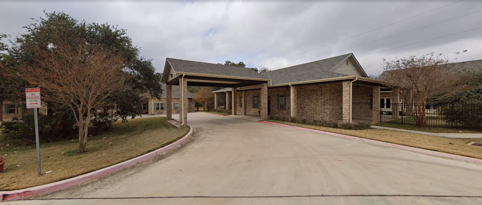 Exterior view of a brick senior living facility entrance with a covered driveway.