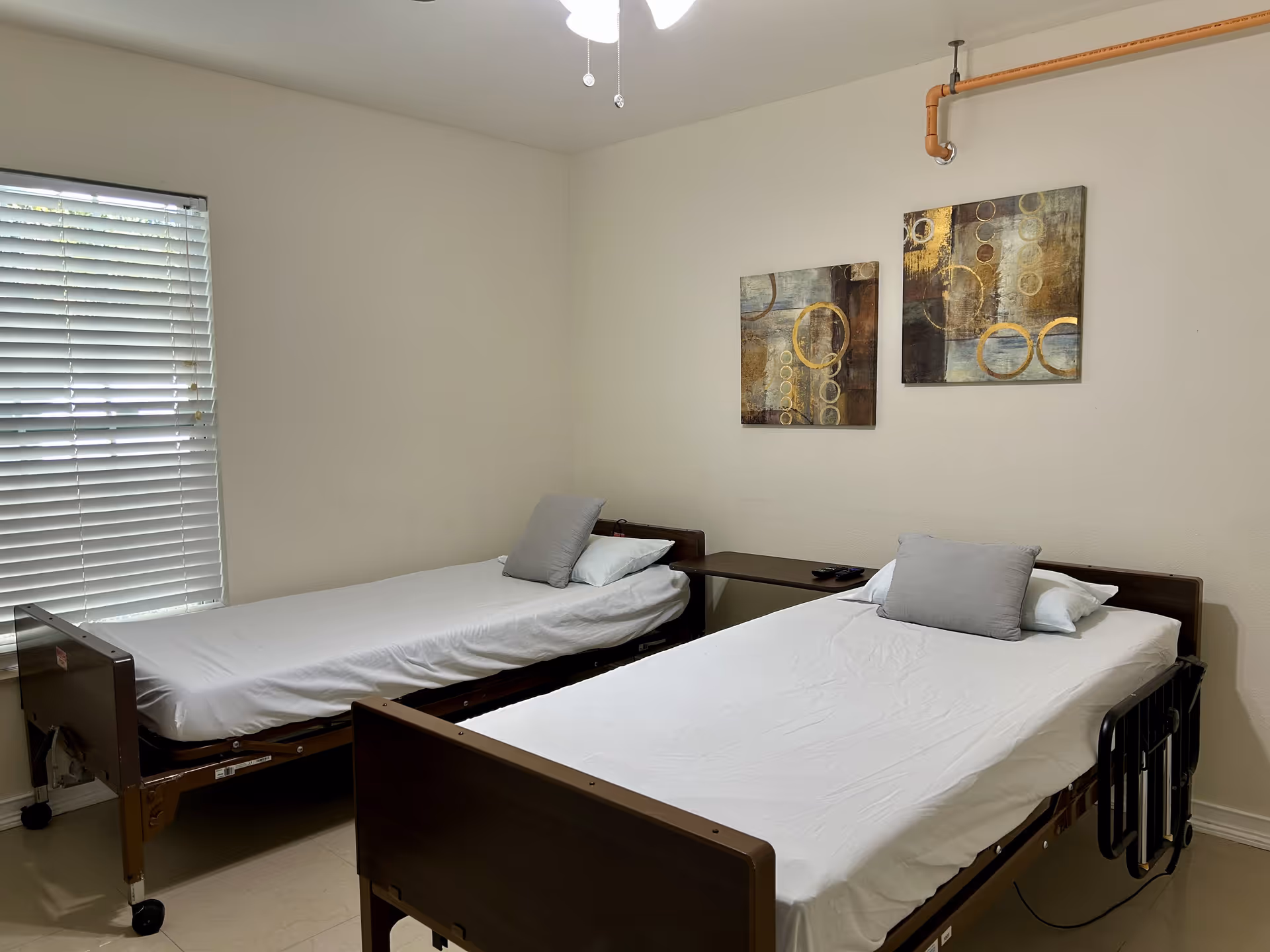 Two twin hospital-style beds with white linens in a small, simple bedroom.