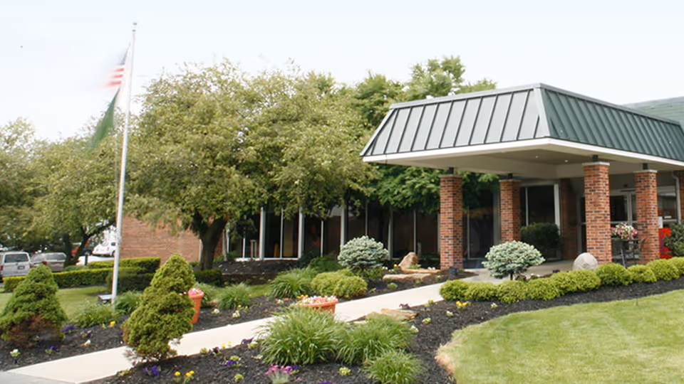 Exterior view of Monterey Care Center entrance with brick columns and landscaped front lawn.