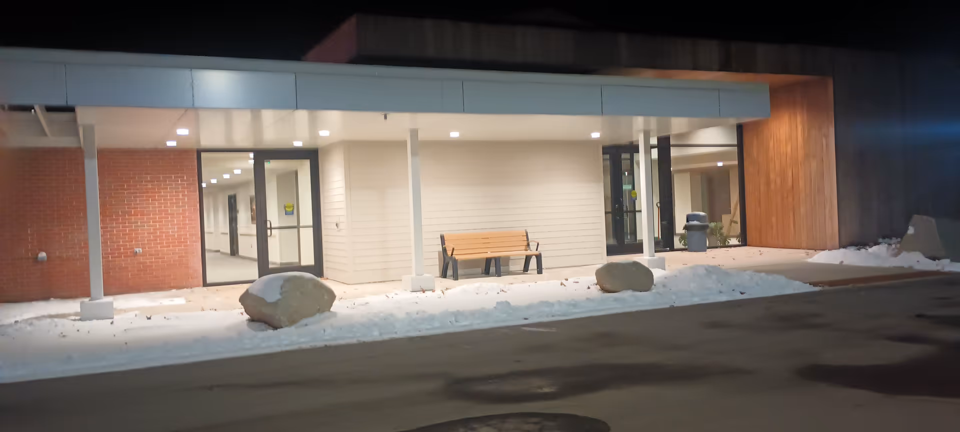 Night exterior view of USA Healthcare Mason City entrance with snow and a bench.