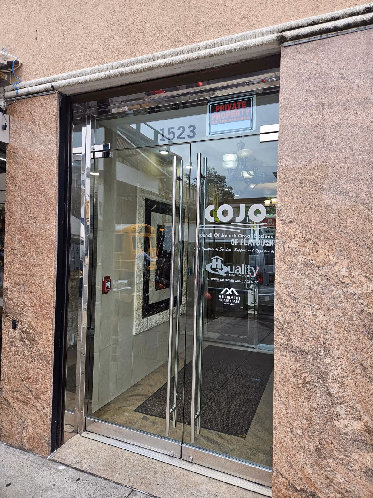 Glass entrance to a Quality Healthcare senior facility with a private property sign