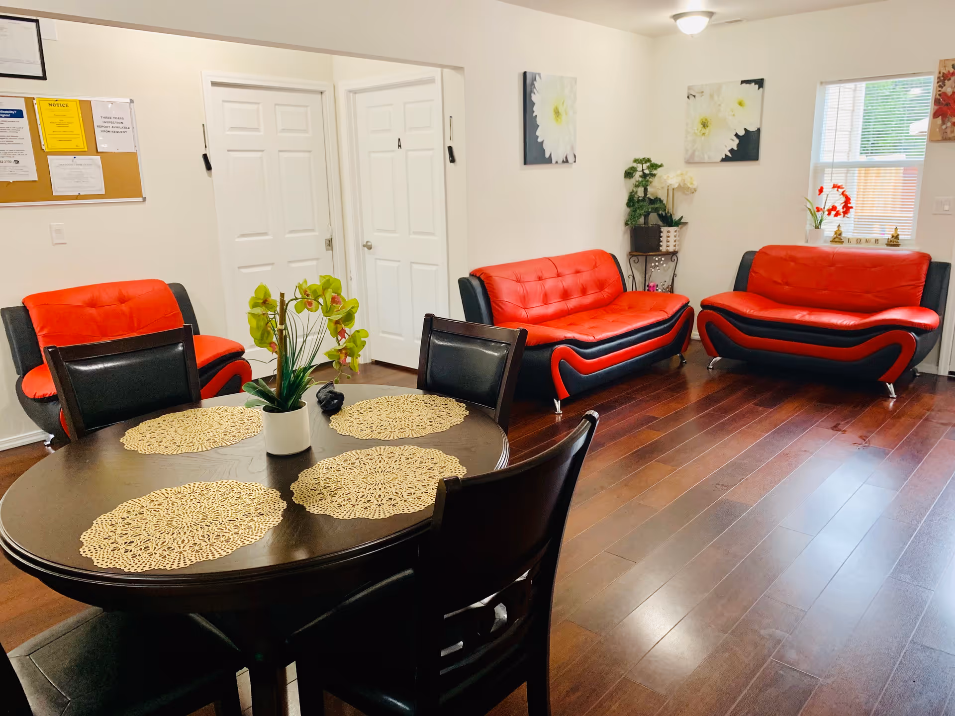 Red and black couches surround a round dining table in a cozy lounge.
