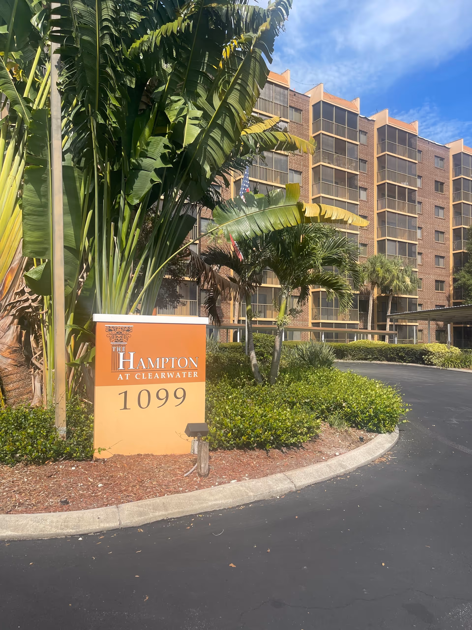 Exterior view of The Hampton at Clearwater, palm trees, and the brick building.