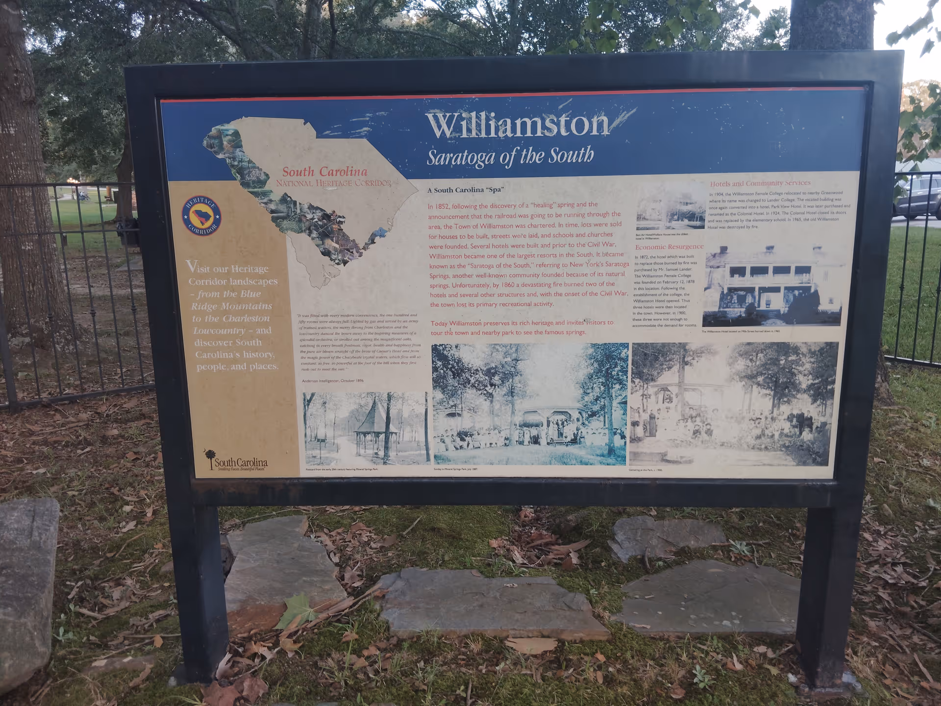 Outdoor informational signboard with maps and historical photos in a park.