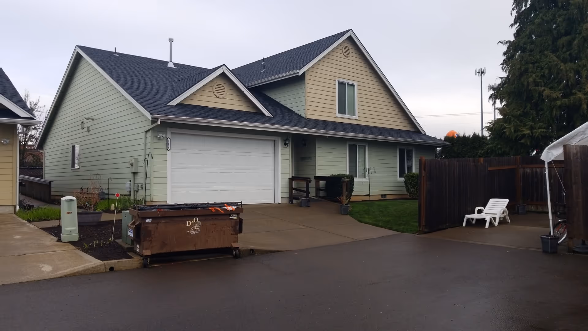 Front view of a green residential-style building with a two-car garage and fenced yard.