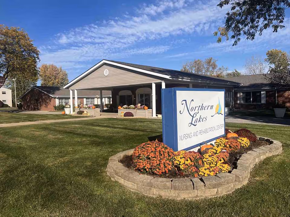 Front view of Northern Lakes Nursing and Rehabilitation Center with landscaped sign and flowers.
