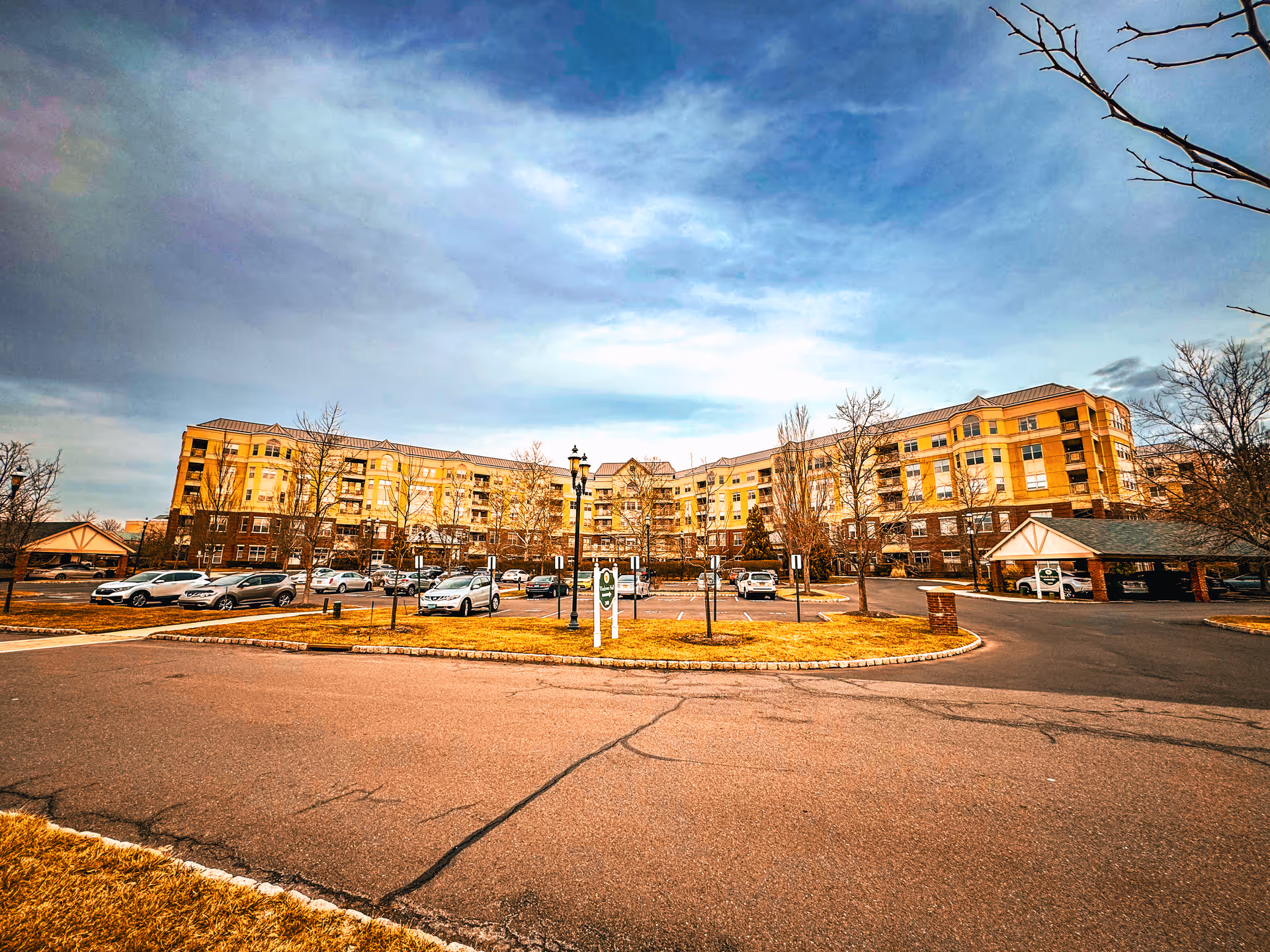 Wide exterior view of Princeton Windrows with curved driveway, parked cars, and a multi-story building.