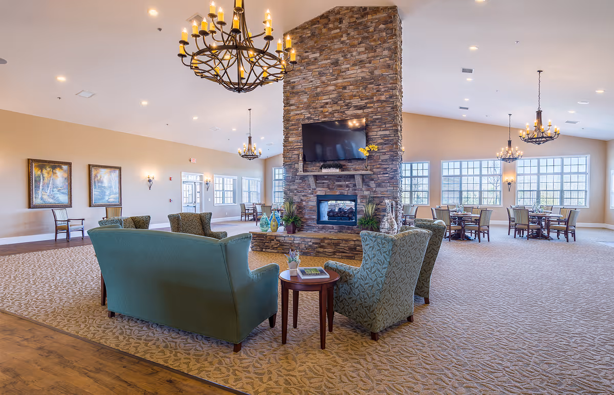 Spacious senior living lounge with a stone fireplace and elegant seating.