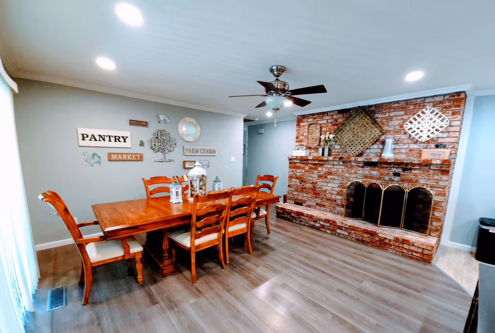 Wood dining table with chairs in a cozy dining room next to a brick fireplace