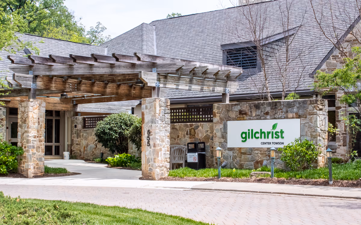 Stone exterior with a wooden pergola framing the entry to Gilchrist Center Towson.
