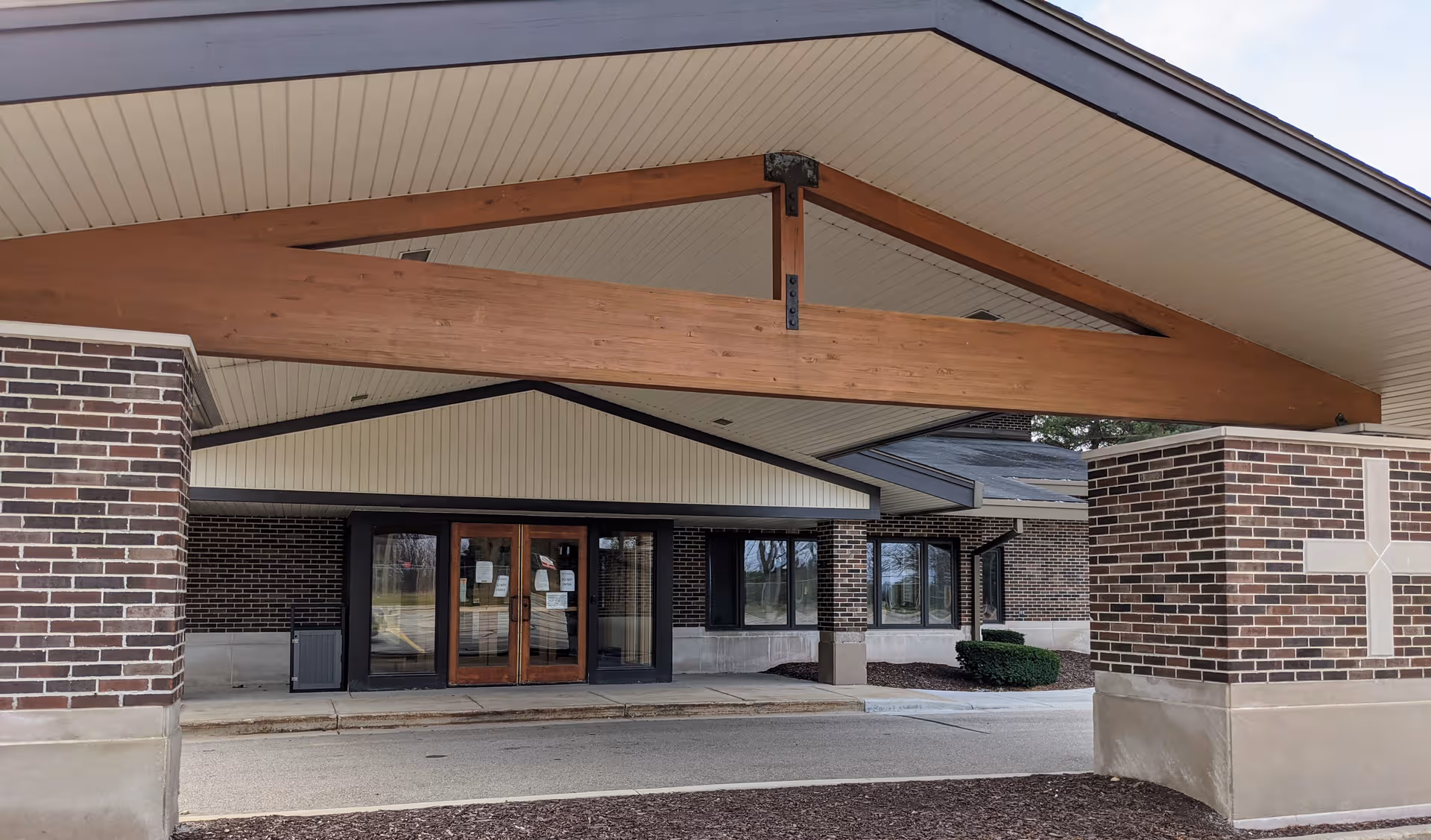Exterior view of Luther Manor entrance with brick columns and a wide covered walkway.