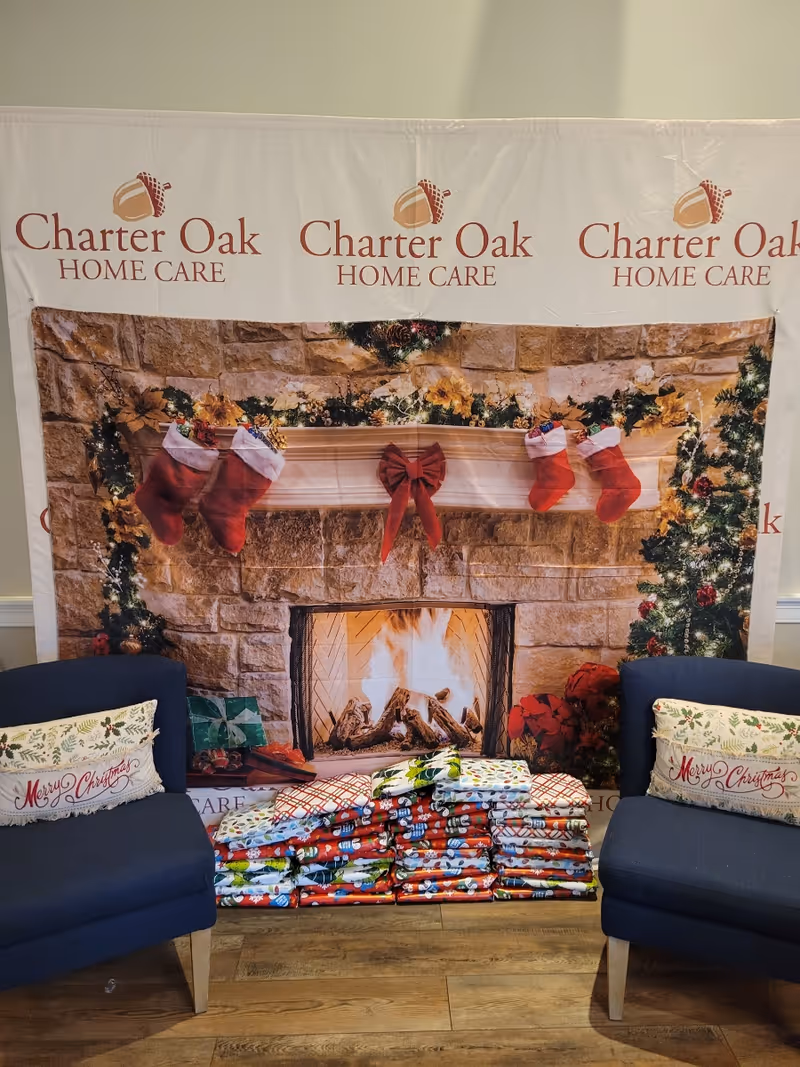 Two blue chairs flank a fireplace backdrop with holiday decor and wrapped gifts.