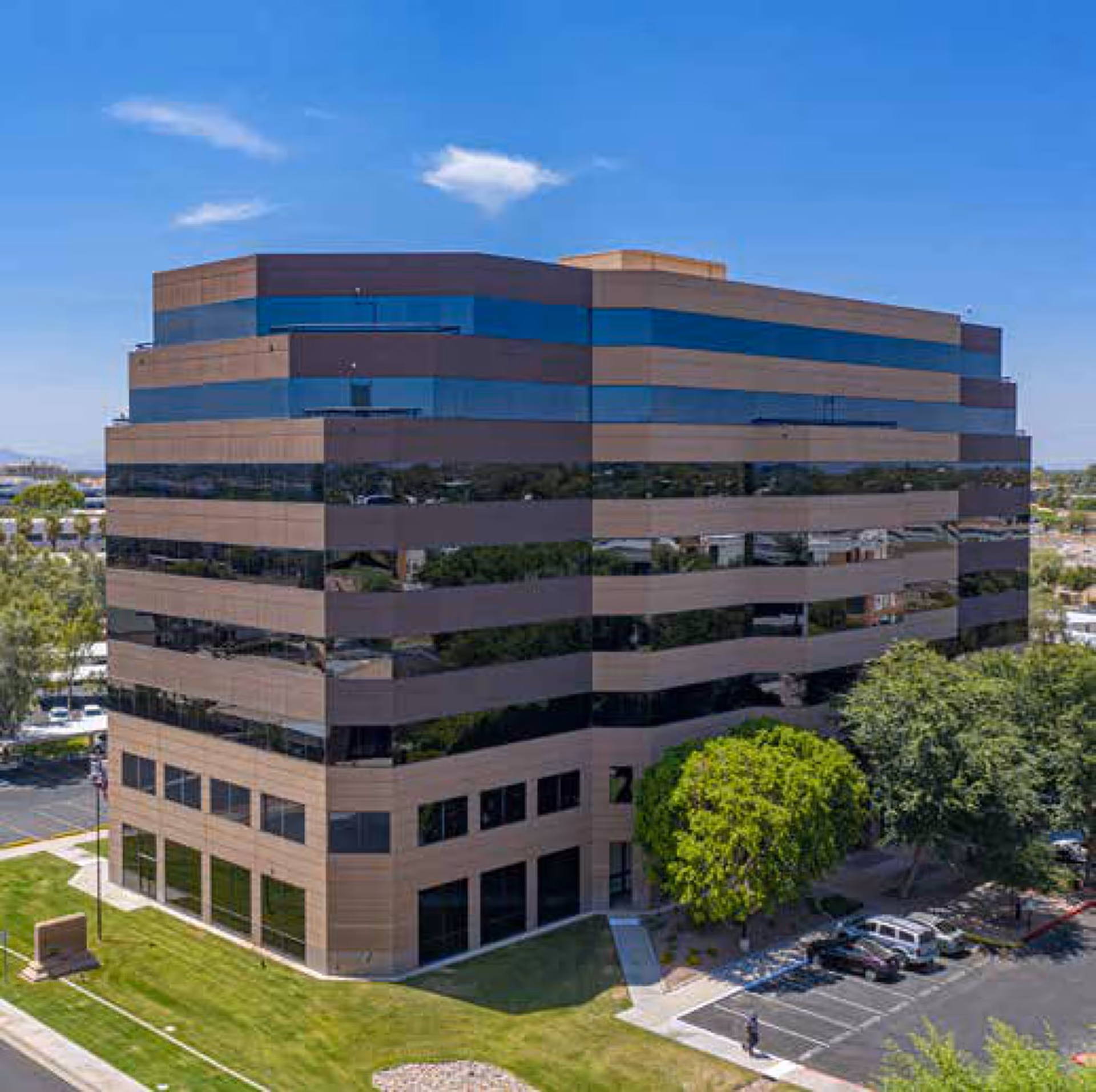 Exterior view of a modern glass building with horizontal reflective bands and trees nearby.