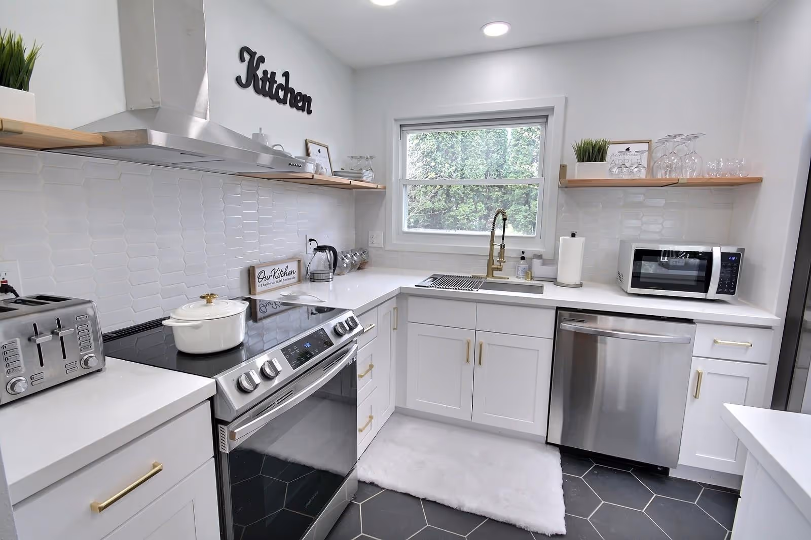 Bright, modern kitchen with stainless appliances, sink, microwave, and white cabinetry.