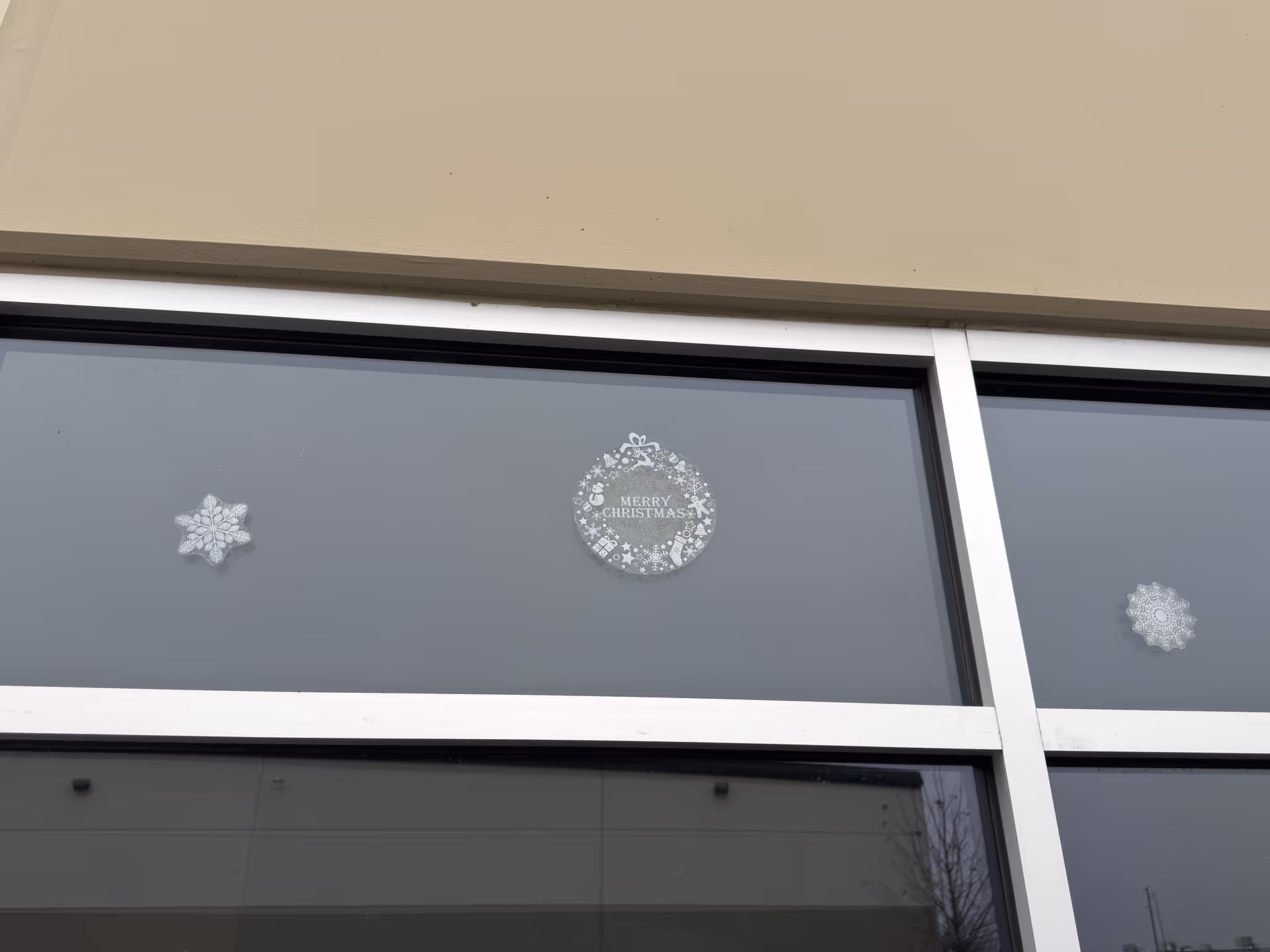 Exterior building window with frosted snowflakes and a Merry Christmas sticker