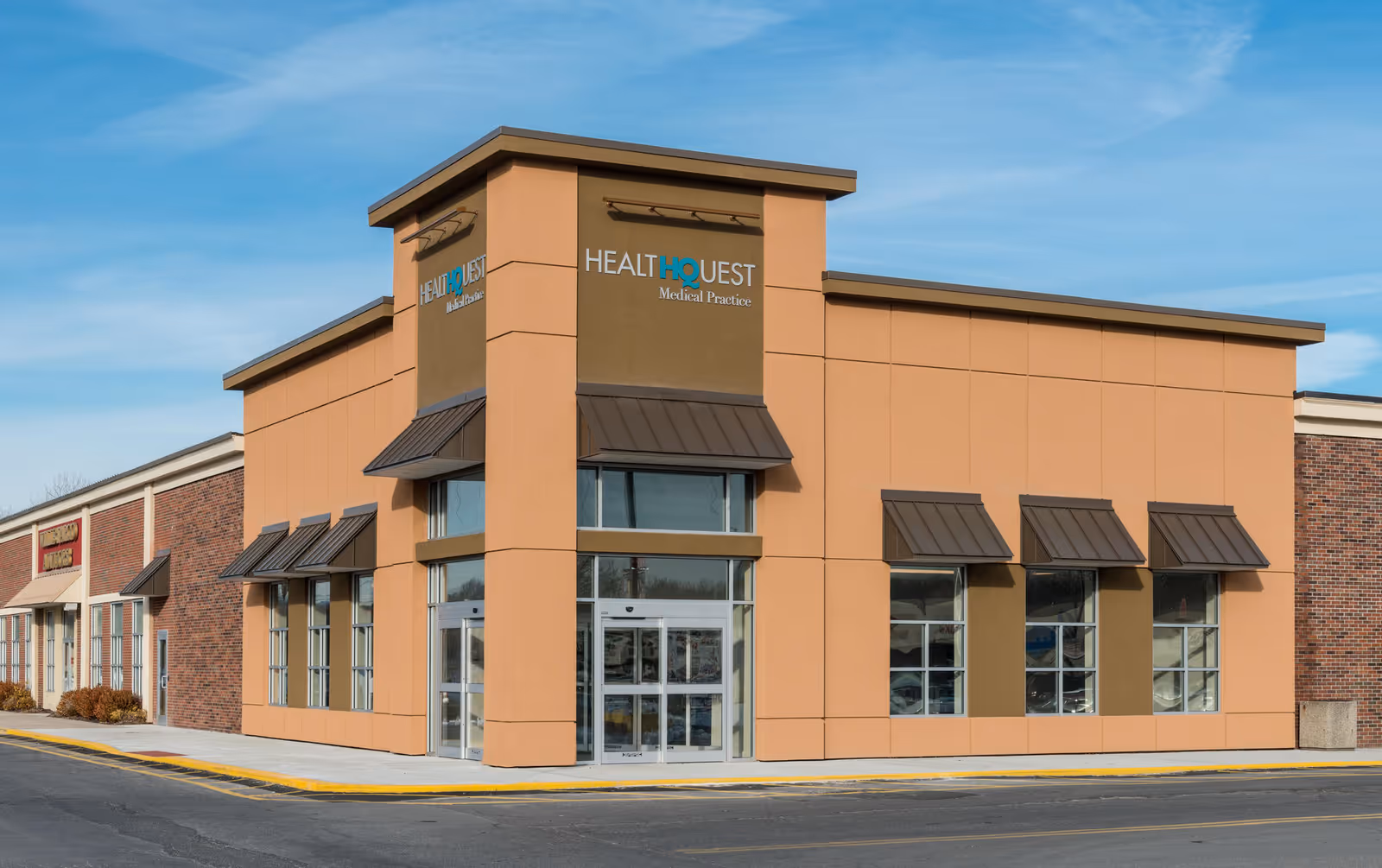 Exterior view of peach-colored medical clinic with large windows and HealthQuest signage.