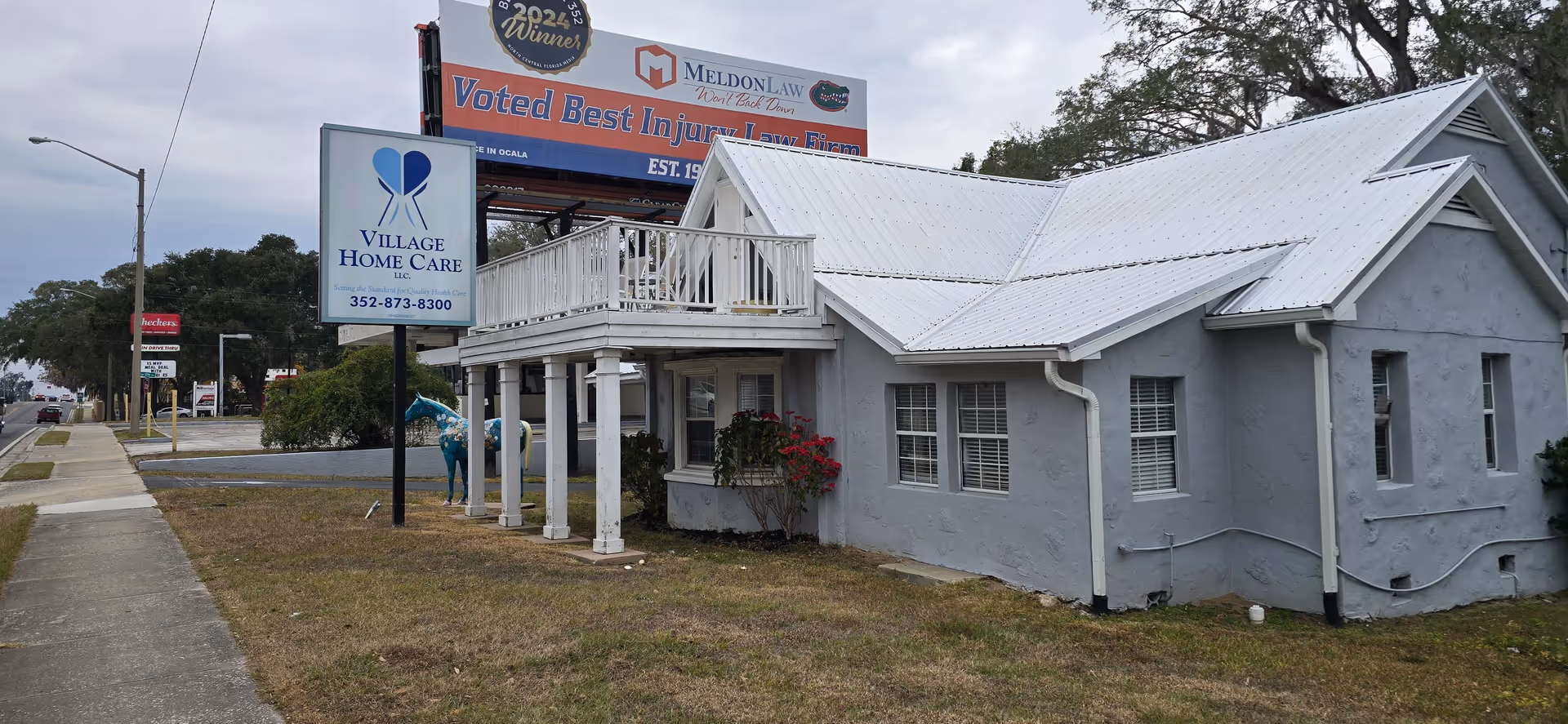 Gray two-story building exterior with Village Home Care sign and a front balcony.