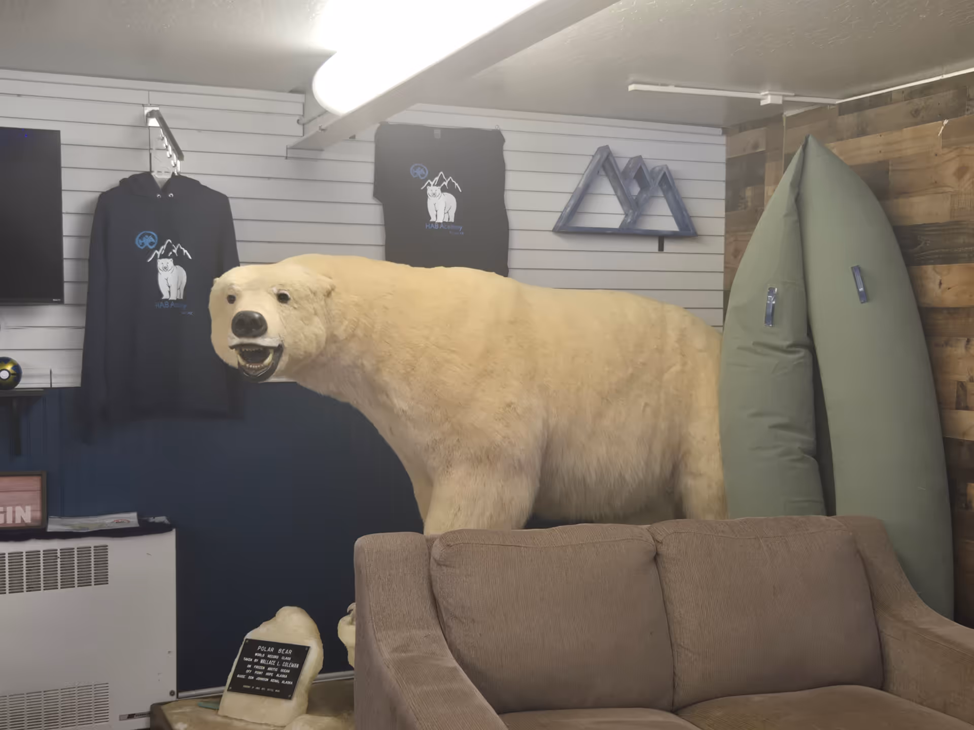 Life-size polar bear figure stands over a tan sofa in an indoor lounge.