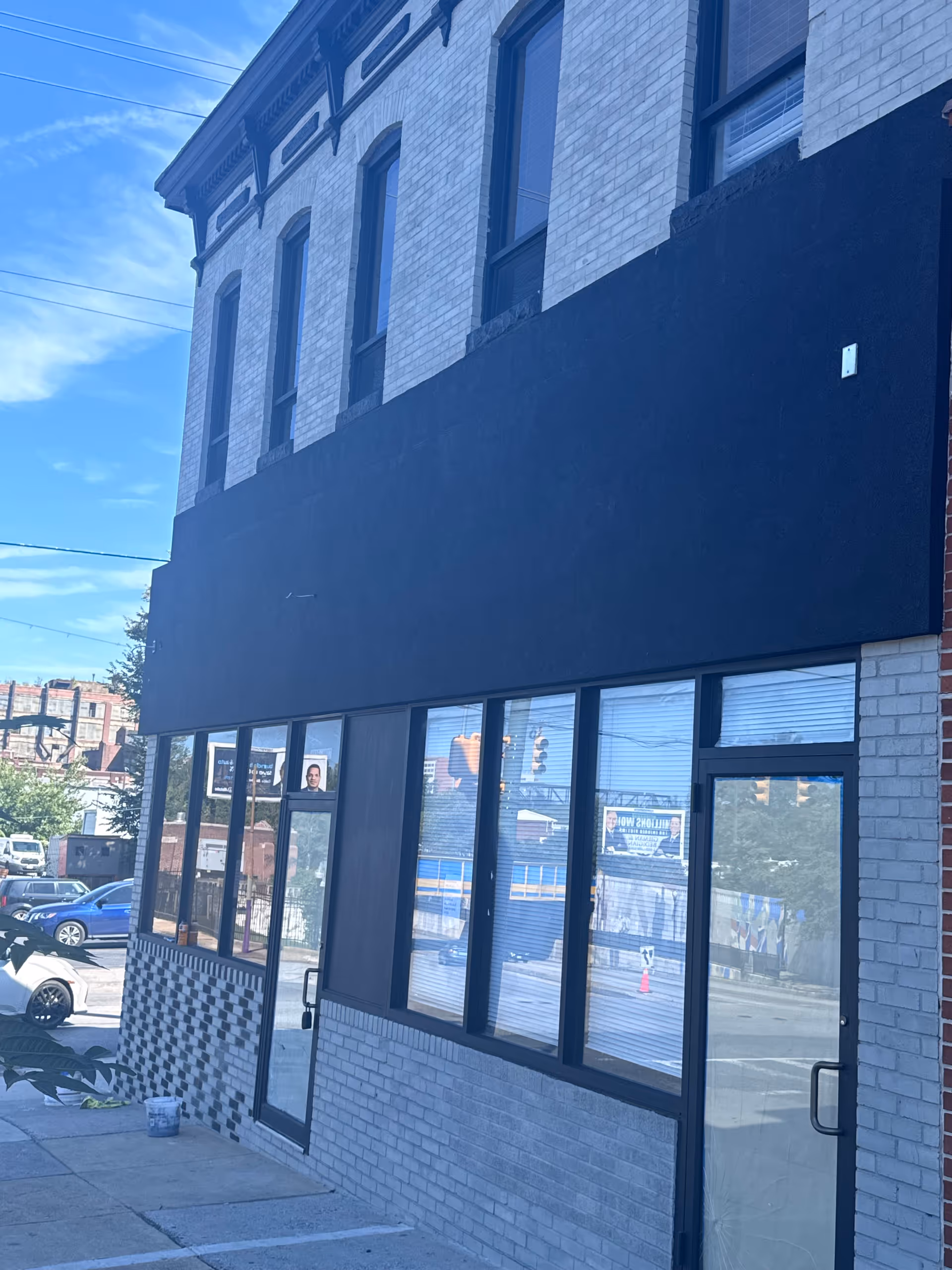 Two-story brick building with large storefront windows and a dark upper facade.
