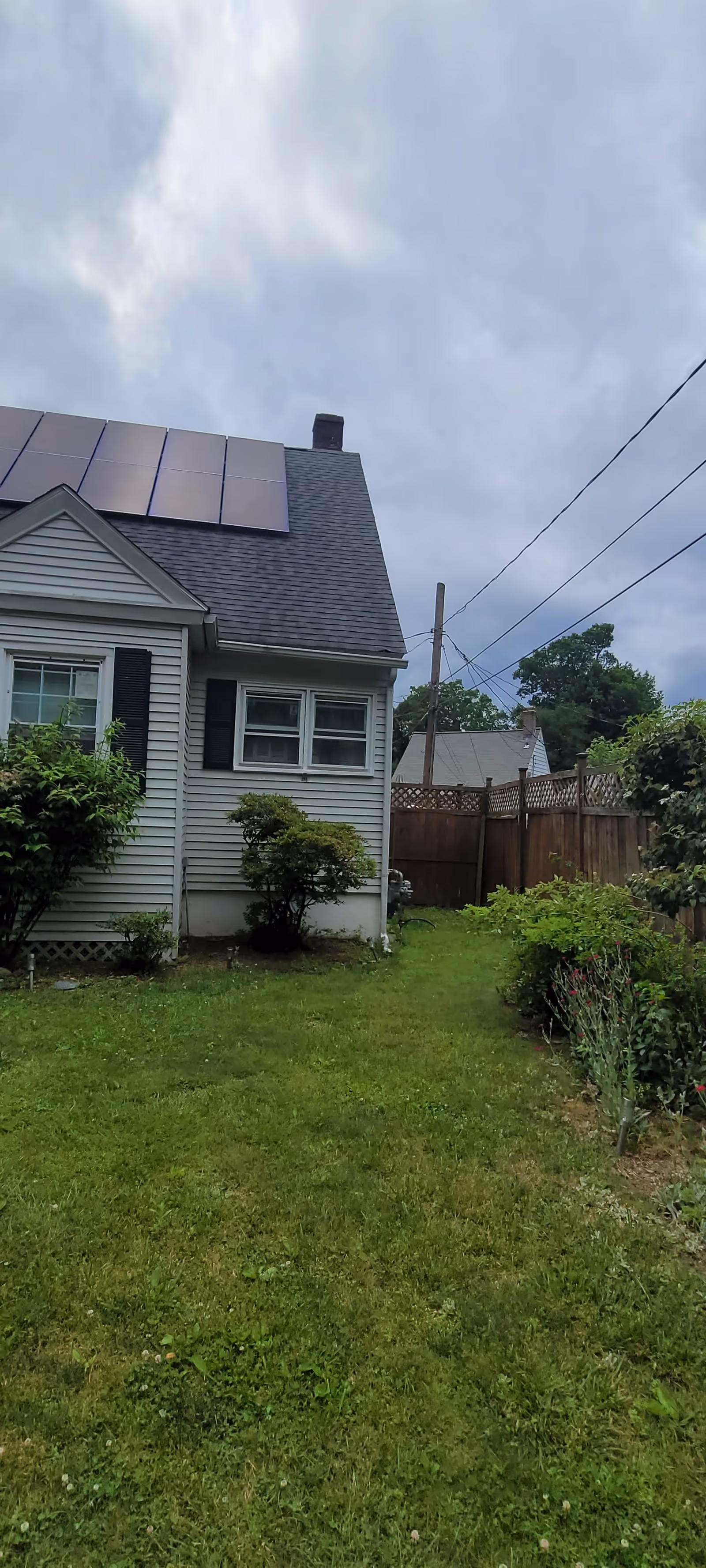 Residential house exterior with solar panels on the roof and a green yard.