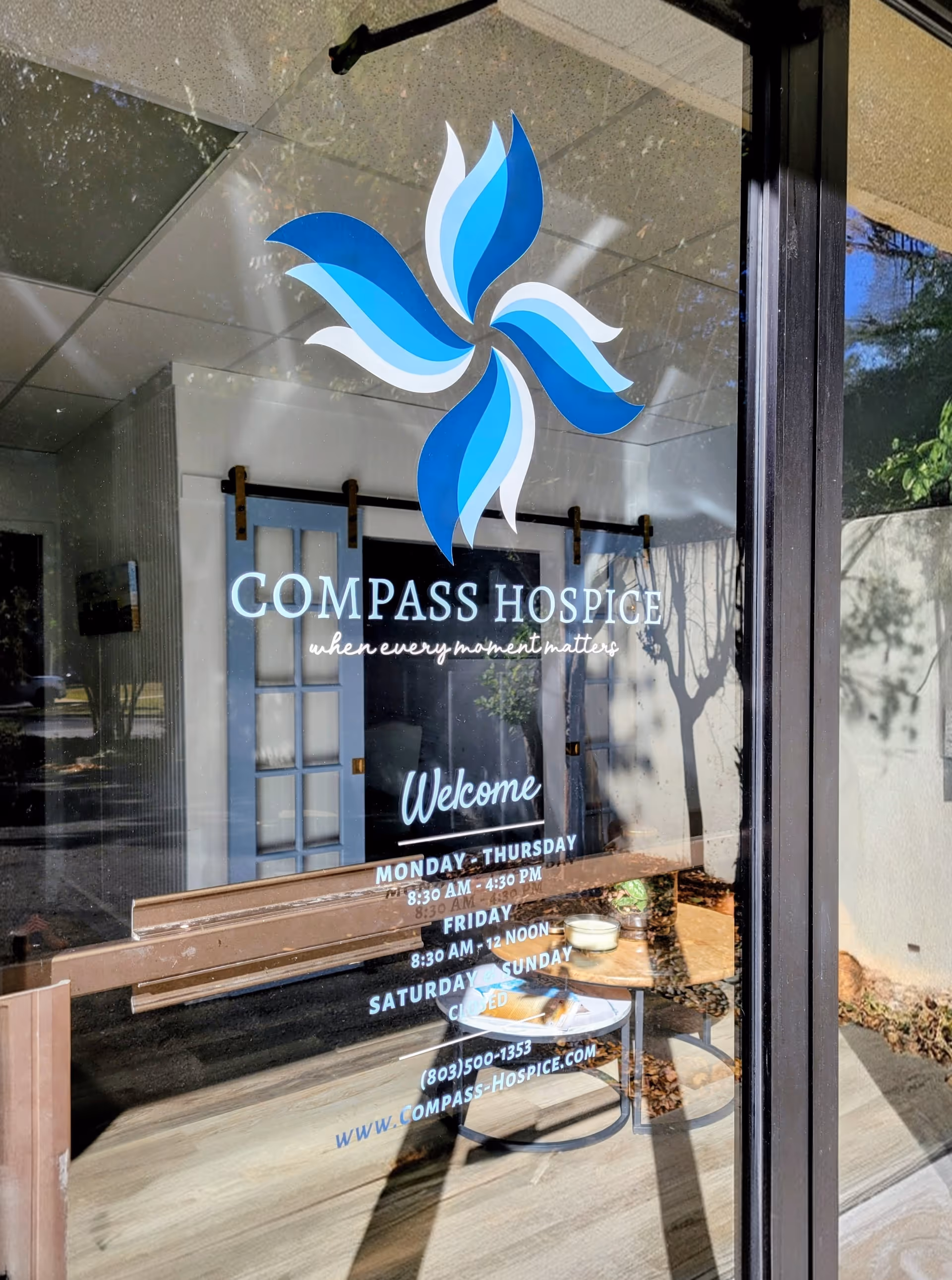 Glass storefront with Compass Hospice logo and welcome text at the entrance.