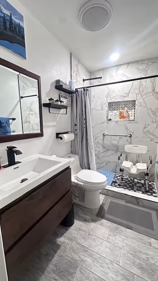 Accessible bathroom with sink, toilet, and shower chair in Adelanto Care Manor.