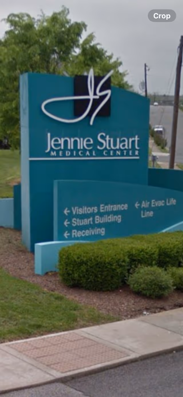 Teal Jennie Stuart Medical Center sign with directional arrows at a landscaped entrance.