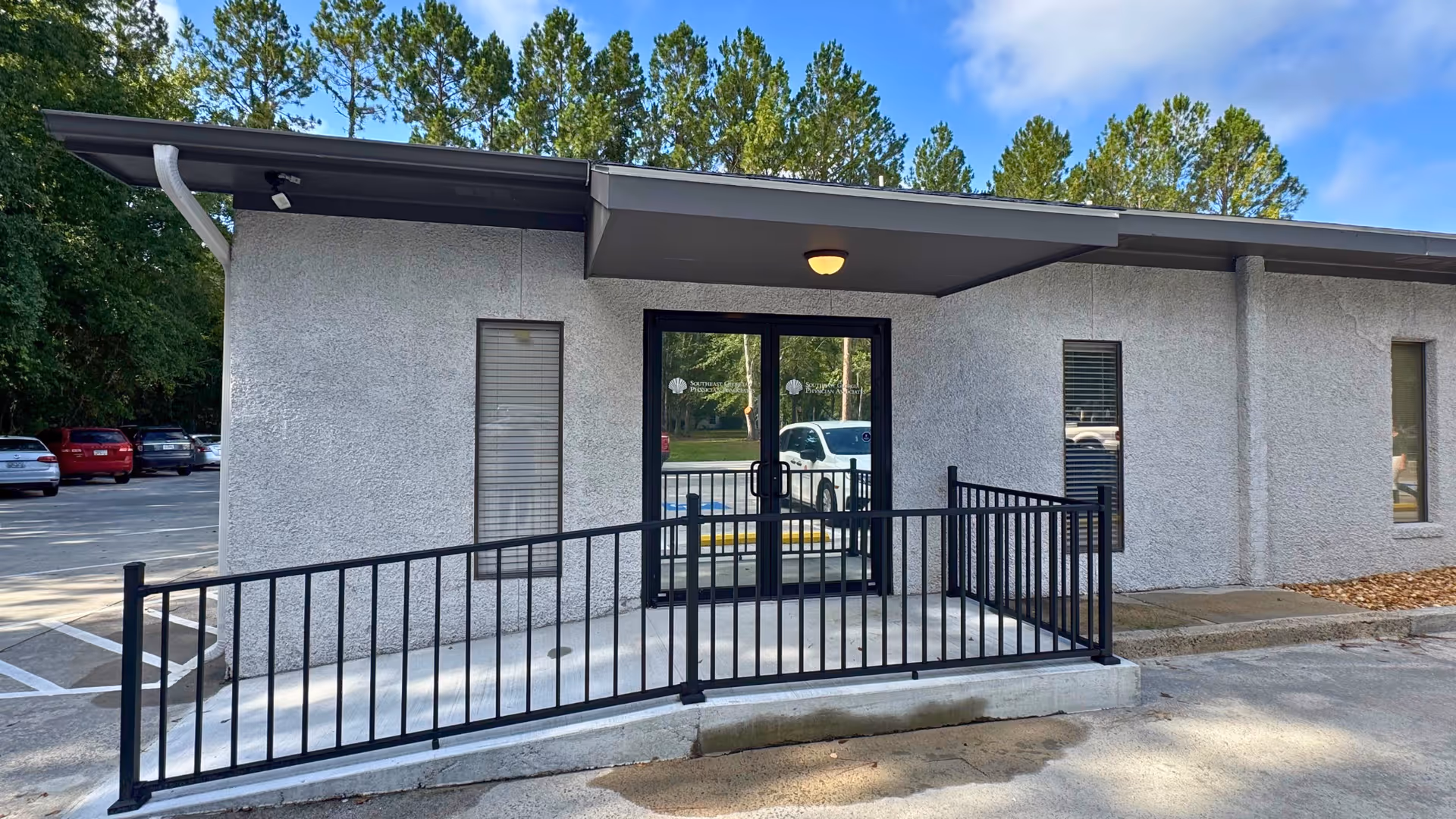 Exterior view of a small medical office entrance with a ramp and glass door.