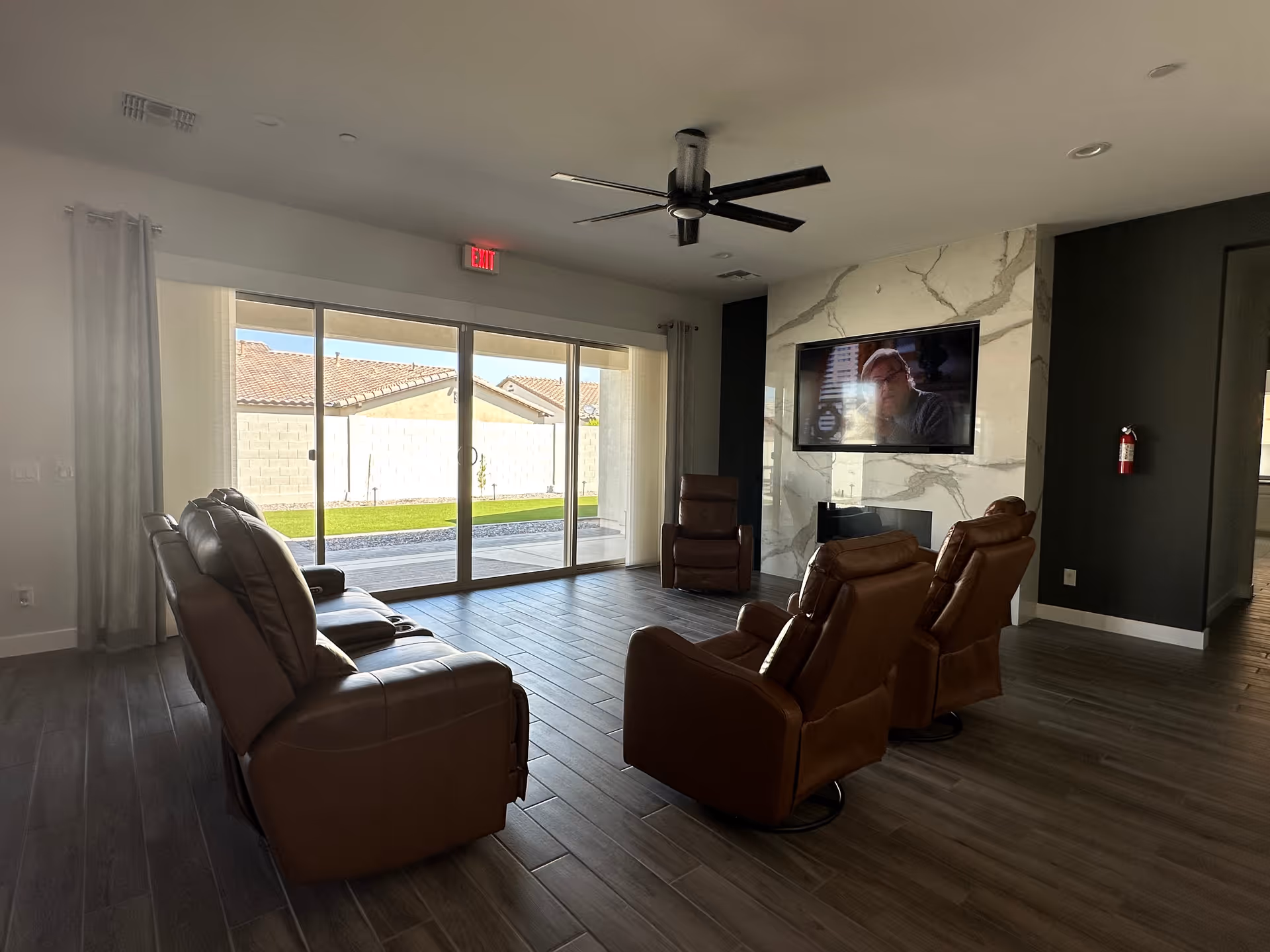 Spacious living room with brown leather recliners, a TV, and sliding glass doors.