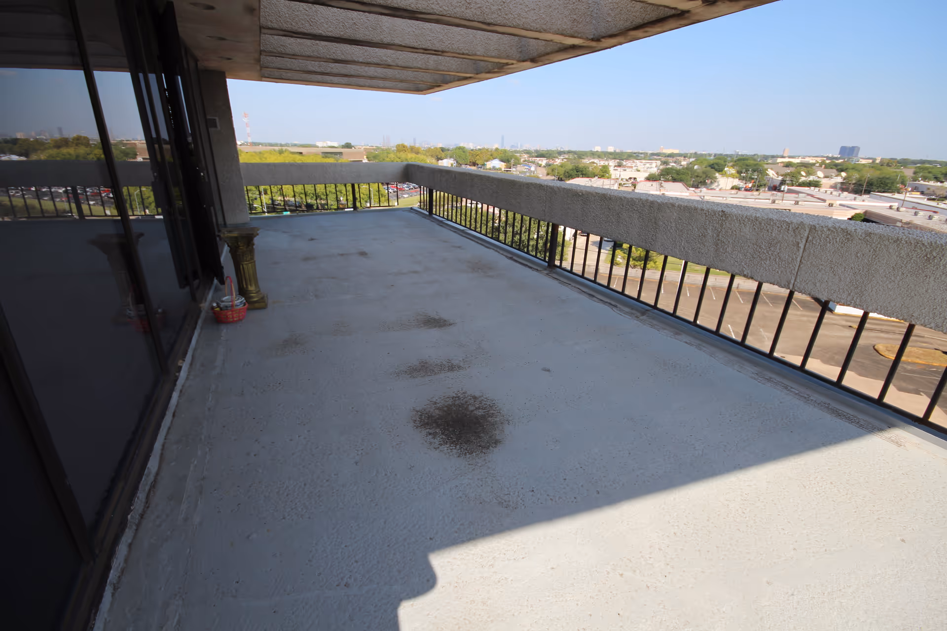 Wide balcony with railing overlooks a distant cityscape
