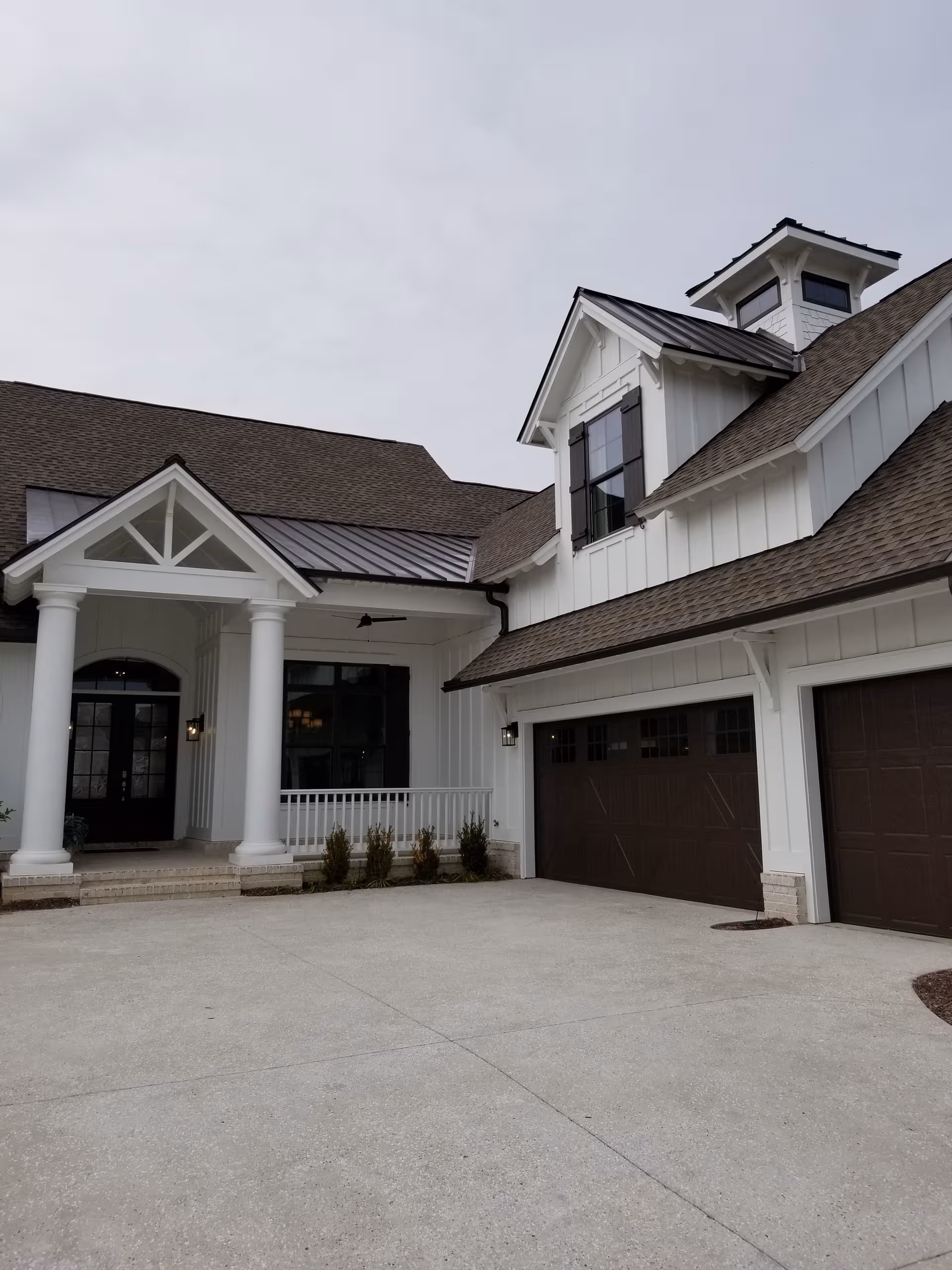 White, modern senior living facility exterior with front porch, columns, and a two-car garage.