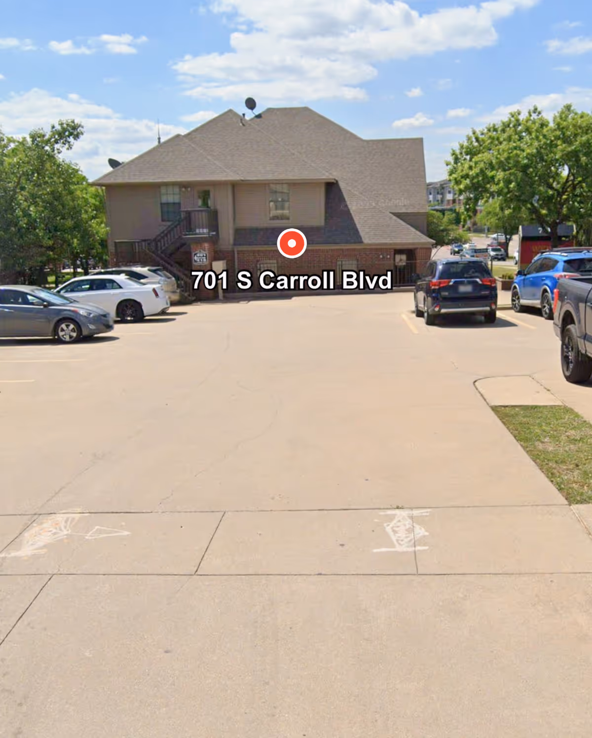 Exterior view of a brown two-story senior care building with a parking lot.