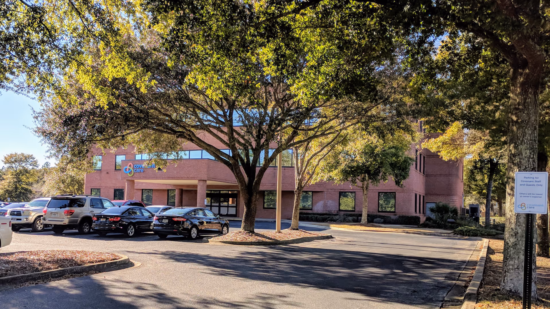 Brick Covenant Care building exterior with a parking lot and trees.