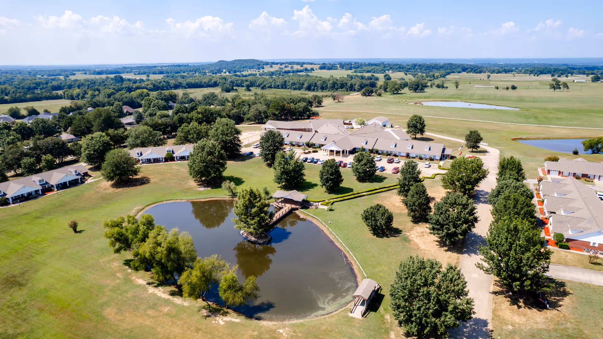 Aerial view of Greenhurst Nursing Center campus with pond and trees.