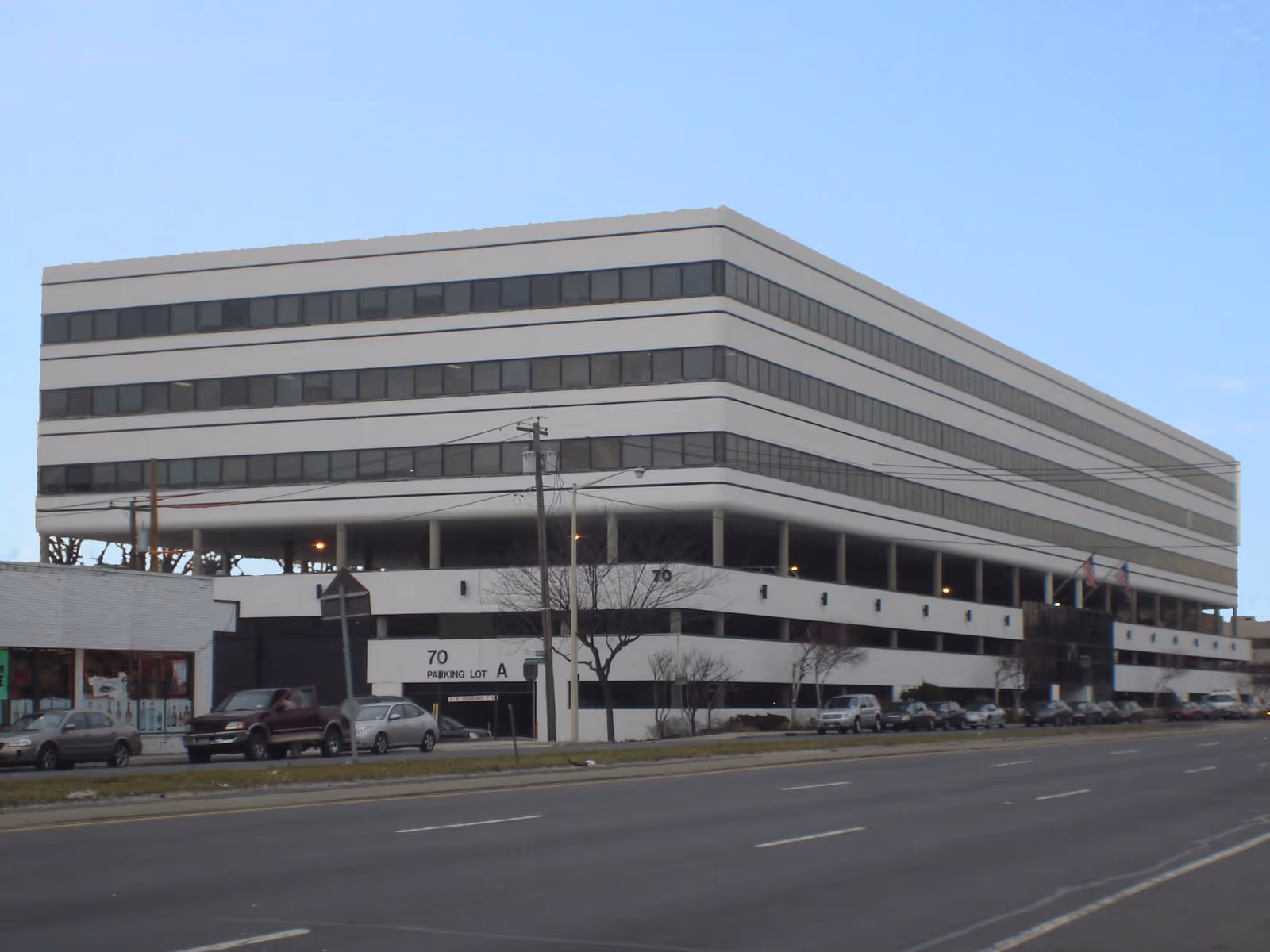 Large modern, multi-story building with street-front parking and several cars.