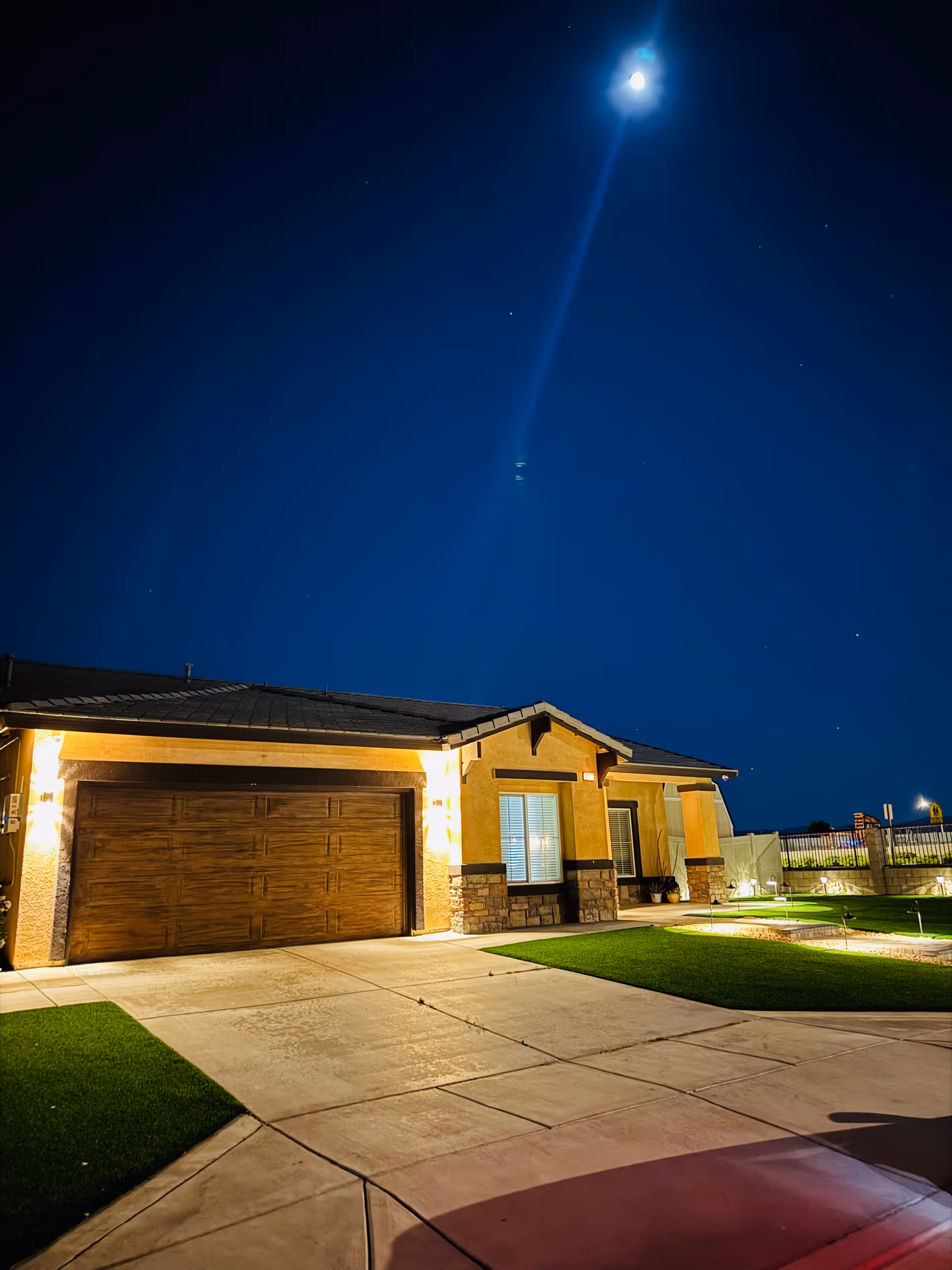 Night exterior of a single-story Oakwood Court Residential Home with lit entrance and garage.