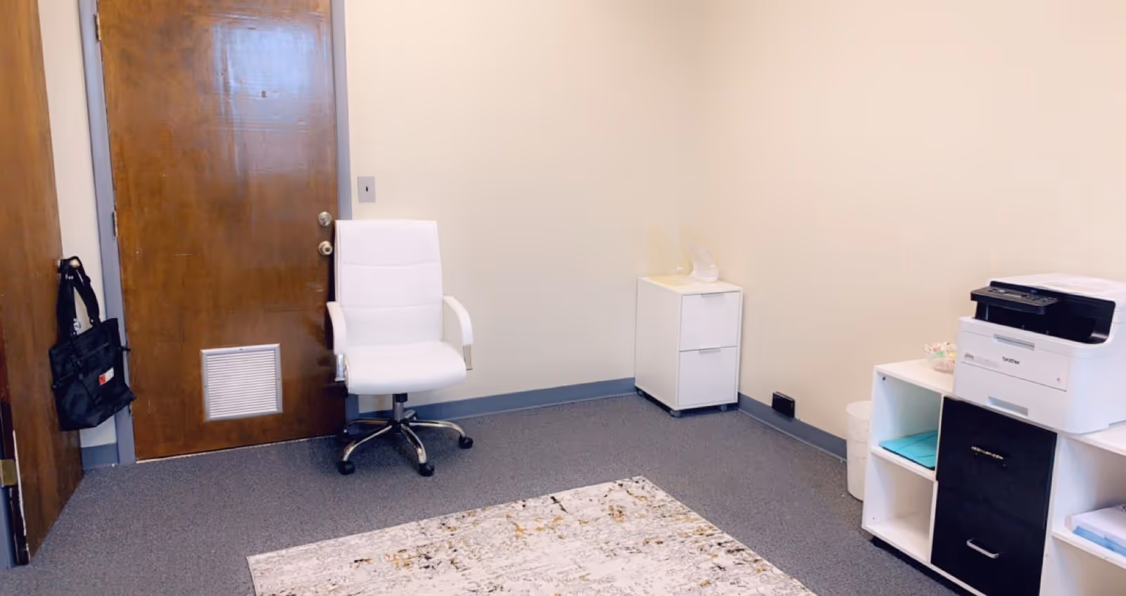 White office chair beside a small cabinet and printer in a quiet, neutral room.