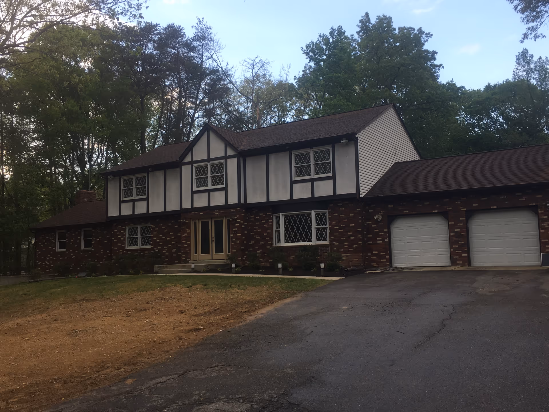 A Tudor-style, two-story brick senior living facility with a driveway and garages.