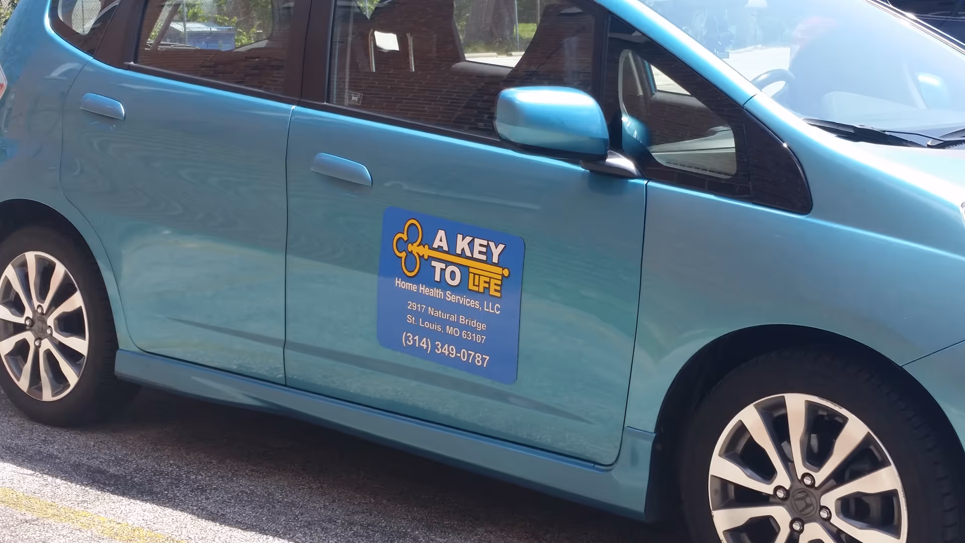 Turquoise van displaying A KEY TO LIFE logo parked outdoors.