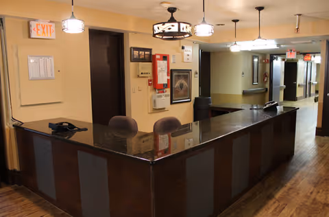 Reception desk in a senior living facility hallway with warm lighting.
