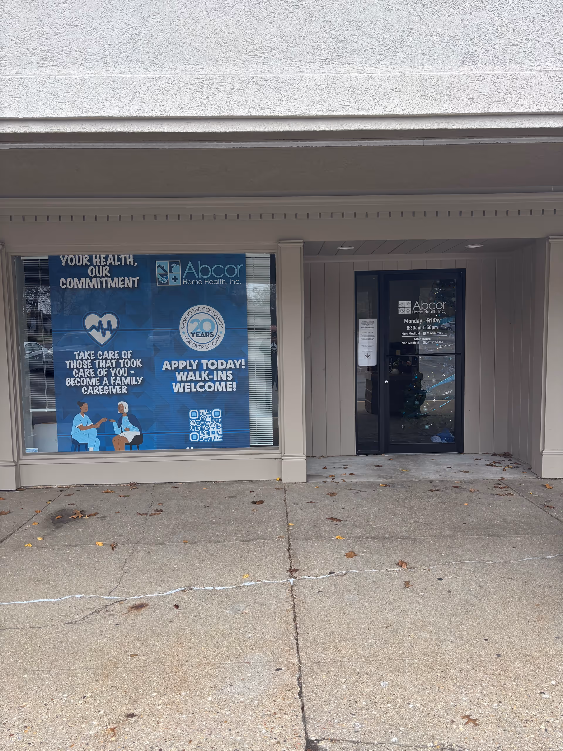 Exterior view of Abcor Home Health facility with blue promotional window signs.