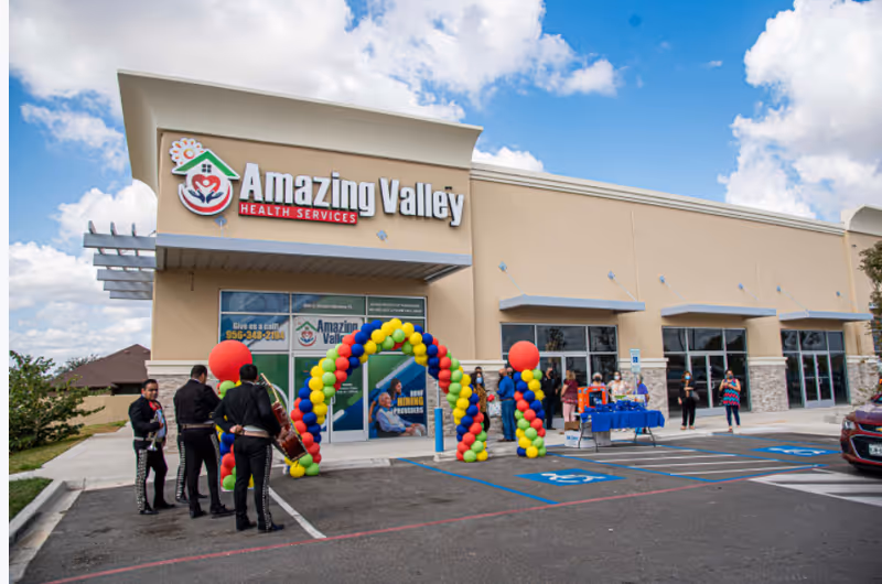 Exterior view of Amazing Valley Health Services with balloon arch and people at the entrance.
