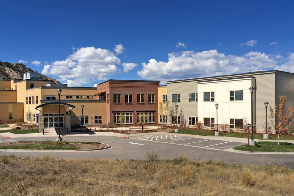Exterior view of a multi-building senior living campus with parking and blue sky