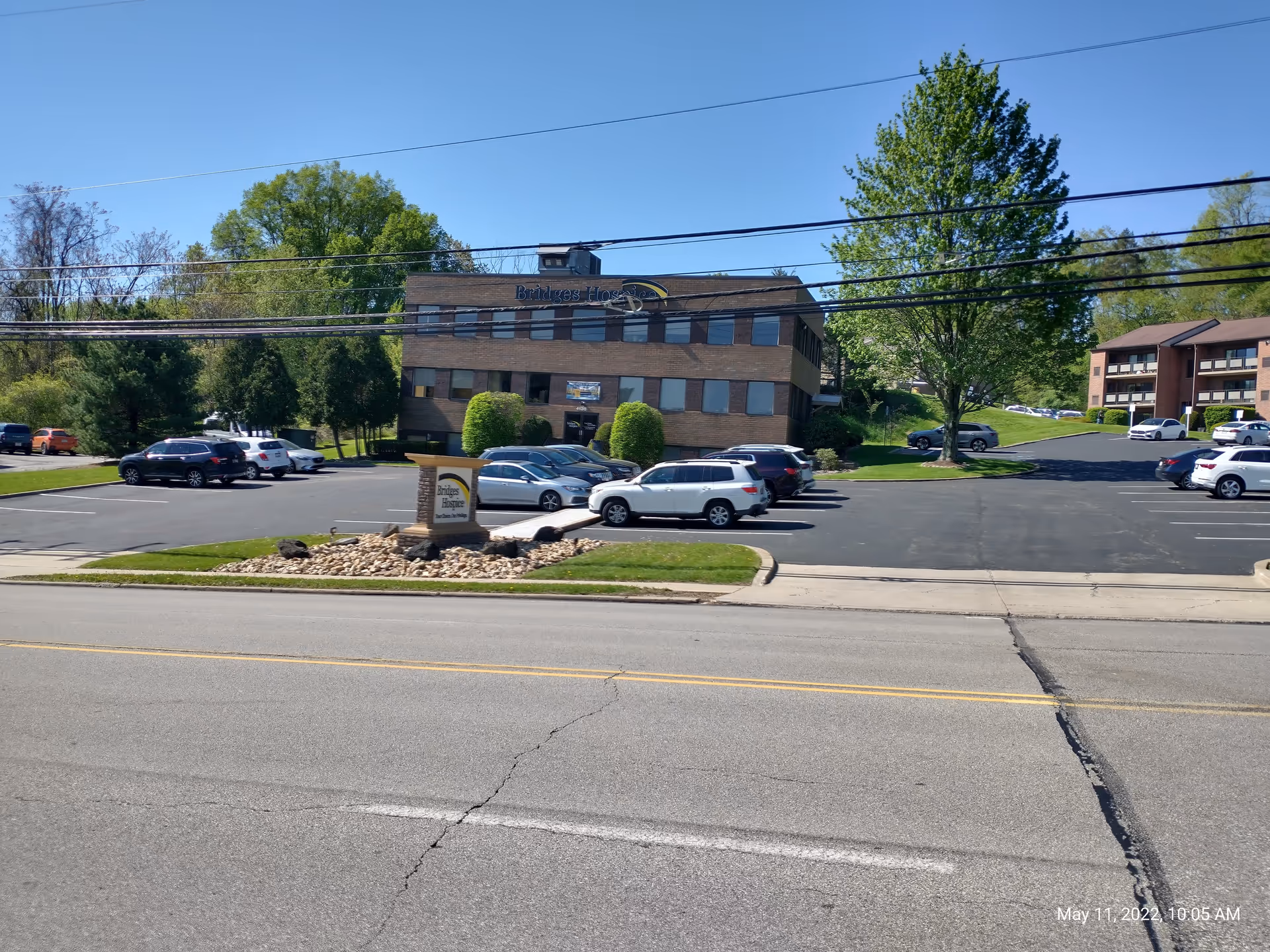 Exterior view of Bridges Hospice building with a parking lot and surrounding trees.