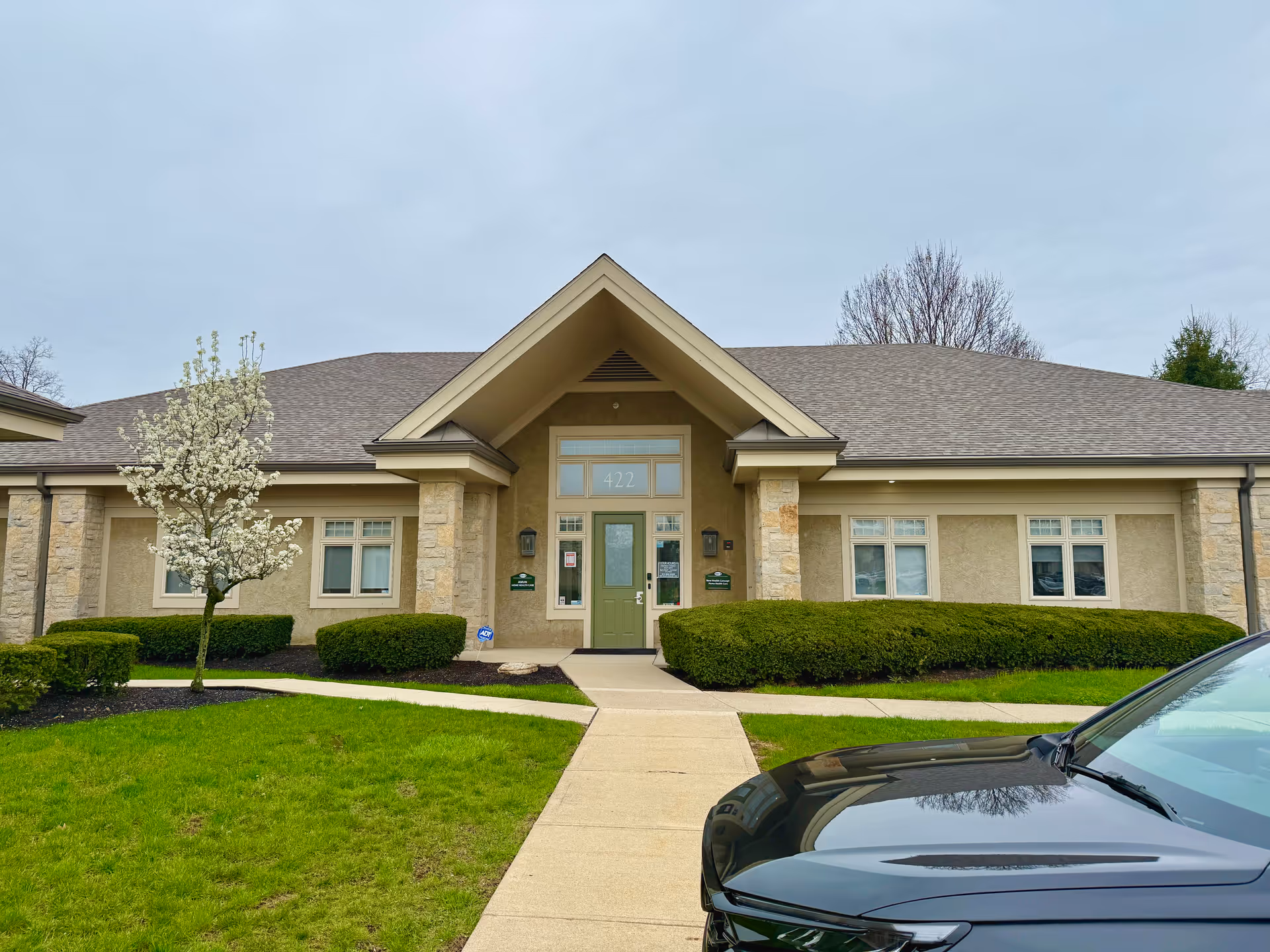 Front view of Amun Home Health Care LLC building with green door, walkway, and car.