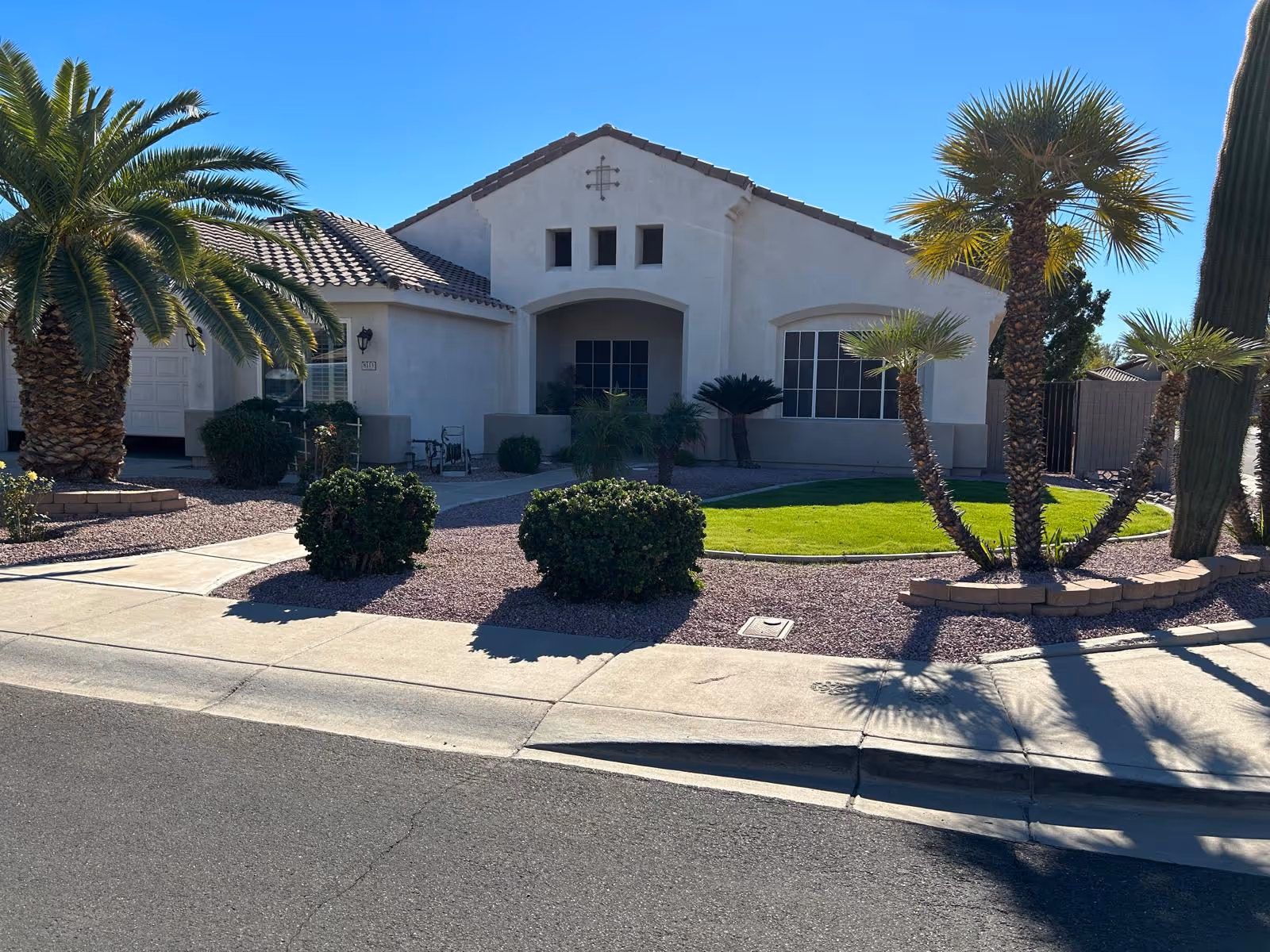 Front exterior of a single-story assisted living home with palm trees and desert landscaping.