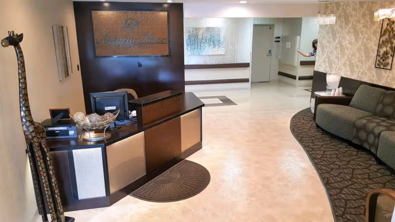 Reception desk in a spacious lobby with seating and wall decor.
