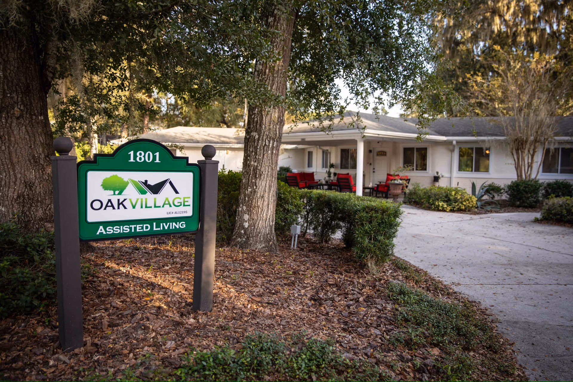 Exterior view of Oak Village Assisted Living with a front sign and outdoor seating.