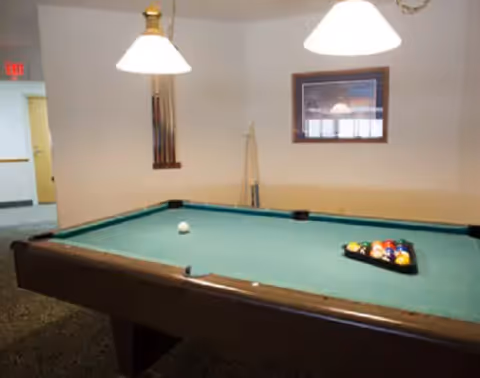 Majestic Pines recreation room with a pool table, cue rack, and overhead lights.