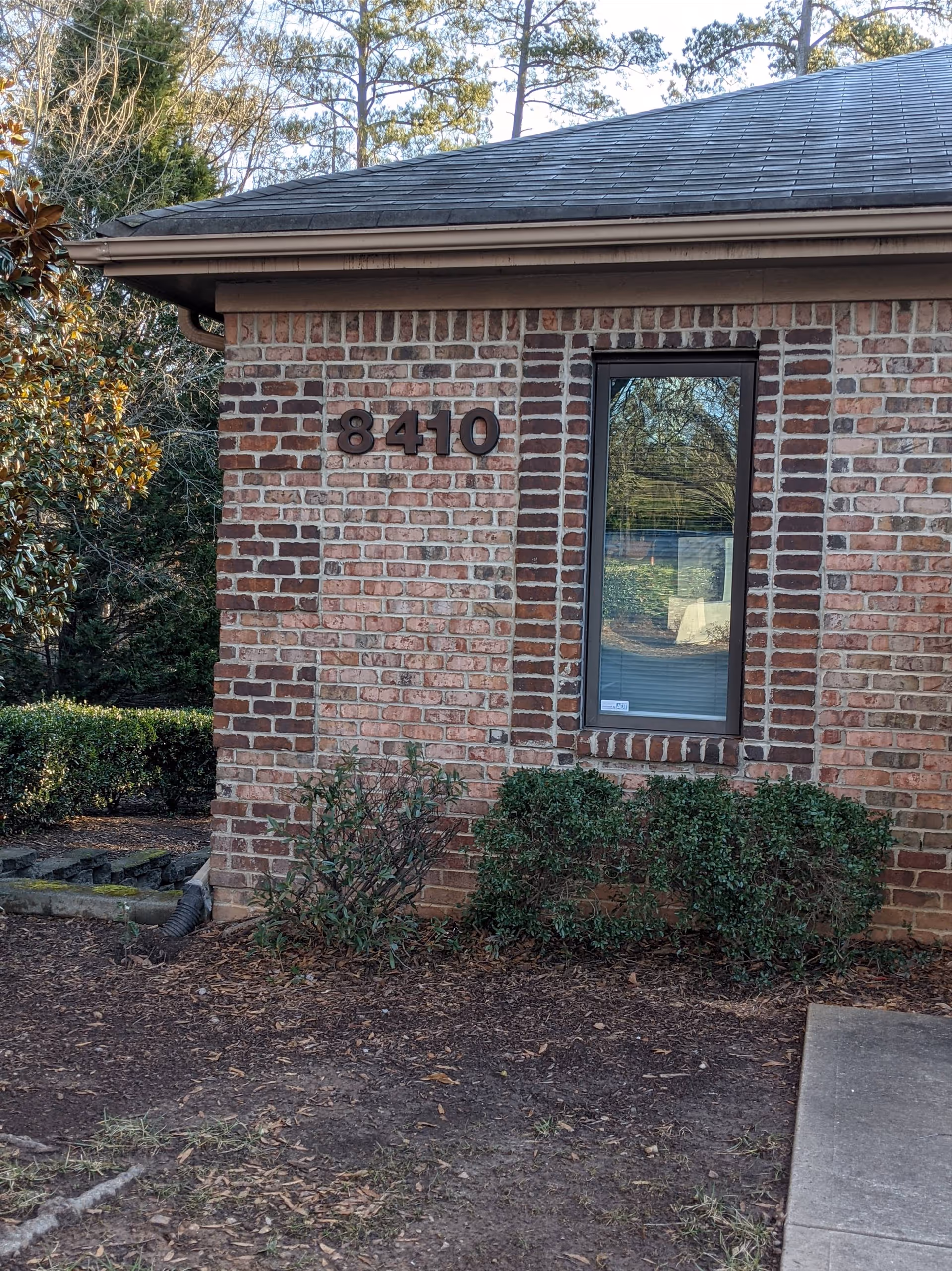 Brick exterior wall with the number 8410 and a window.